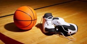 orange basketball ball next to basketball shoes