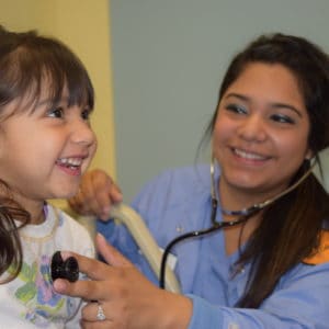 Female nursing student listening to child's heartbeat
