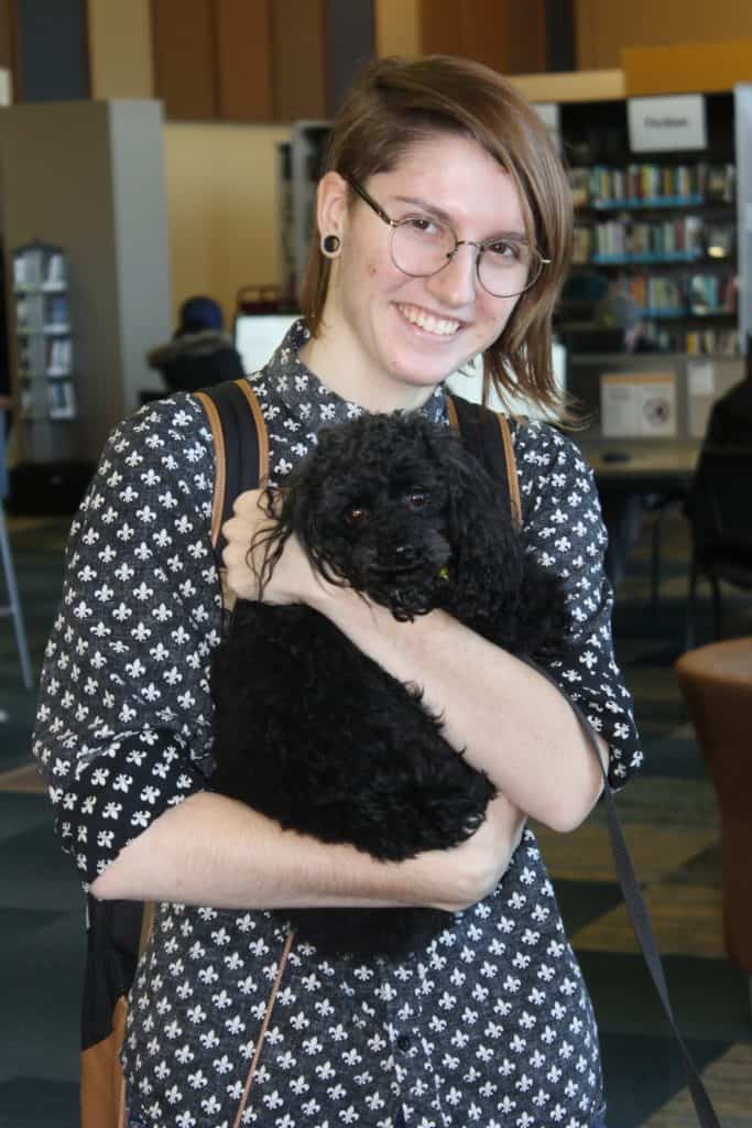 smiling female student holding small black dog