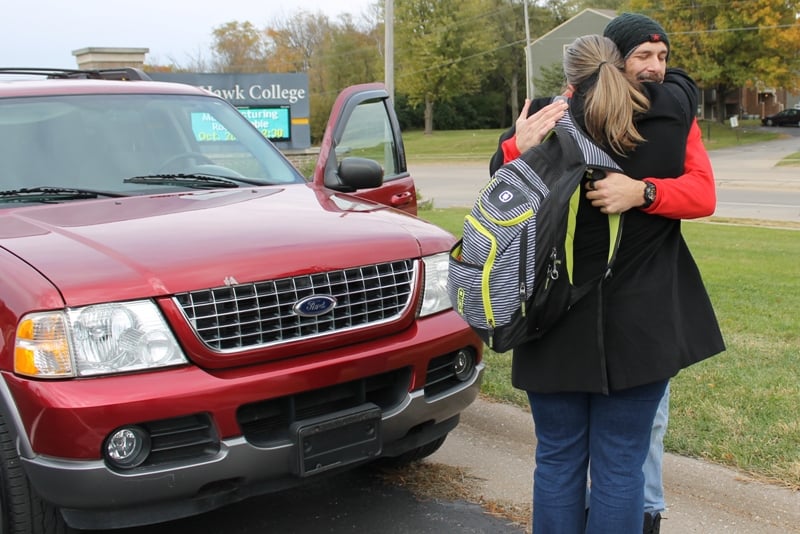 Red Ford Explorer in parking lot with man and woman hugging in front of it