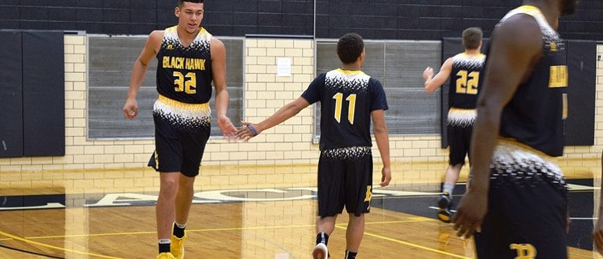 Two men's basketball players high-five on the court