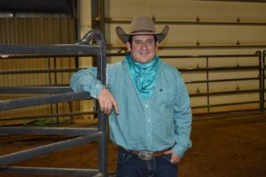 male student dressed in Western clothing standing in Ag Arena