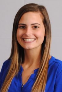 Micaela Beam in front of grey background, wearing blue shirt