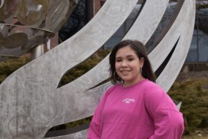 girl in pink shirt standing next to silver BHC logo
