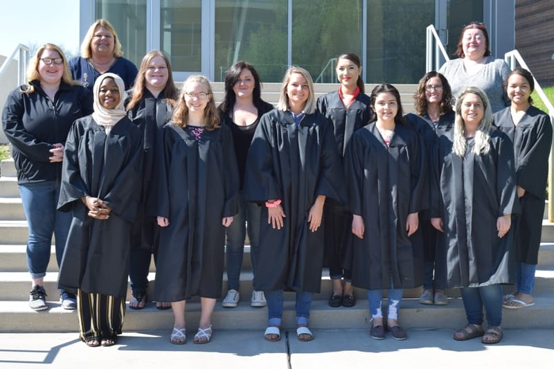 13 women wearing black graduation gowns