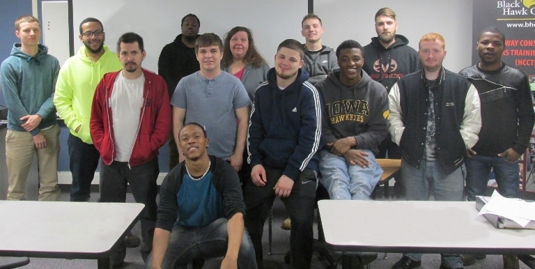 12 men & 1 woman in standing in a classroom
