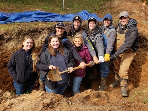 8 college students standing in soils pit