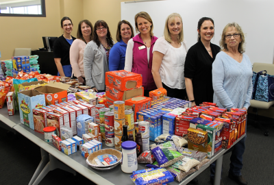 women standing behind a table filled with food pantry items