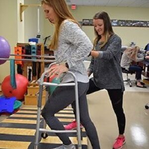 physical therapy assistant helps patient