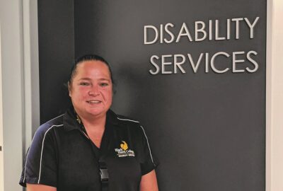 employee wearing Black Hawk College polo stands next to Disability Services entrance