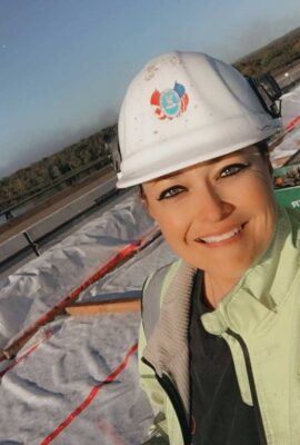 smiling woman in a hard hat at a construction site