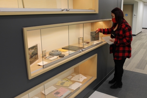 student putting time capsule items in display case