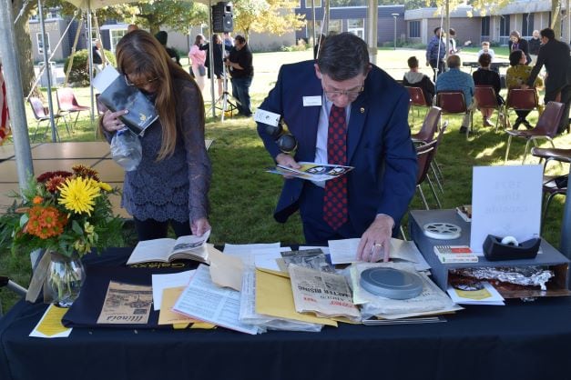 2 people looking at contents of time capsule on a table