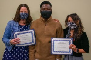 3 people wearing masks and holding certificates