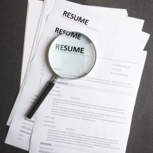 magnifying glass on top of resumes