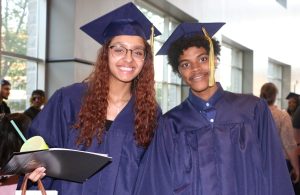 2 grads in caps & gowns smiling at camera