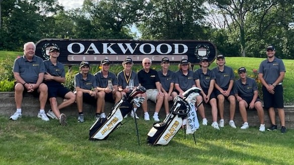 golfers and coaches sitting in front of Oakwood Country Club sign
