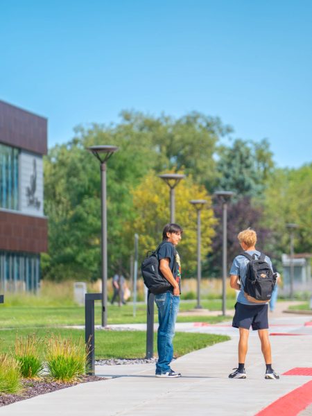 Two students walking on campus path.