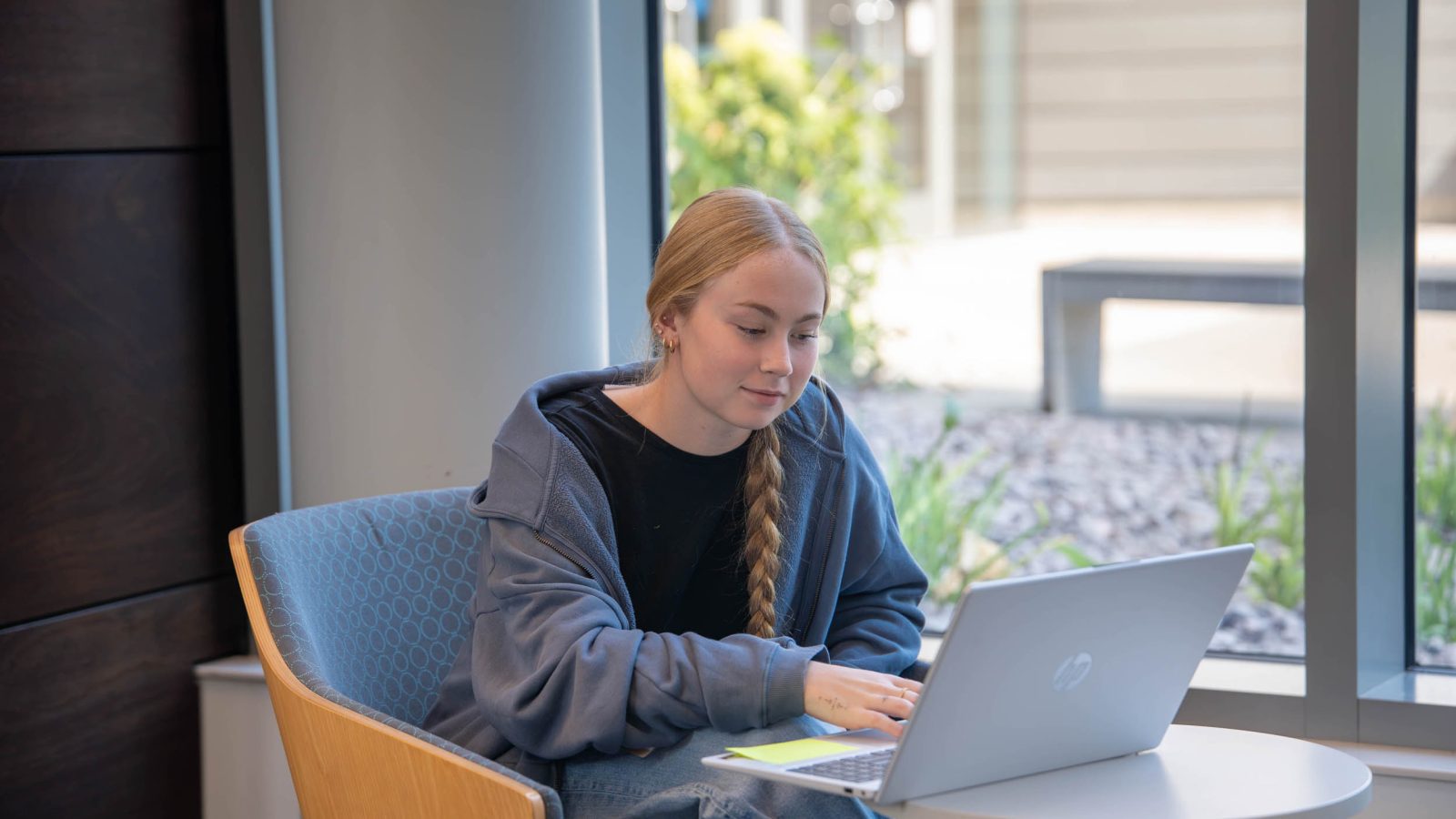 Female student sitting at a table with a laptop open.