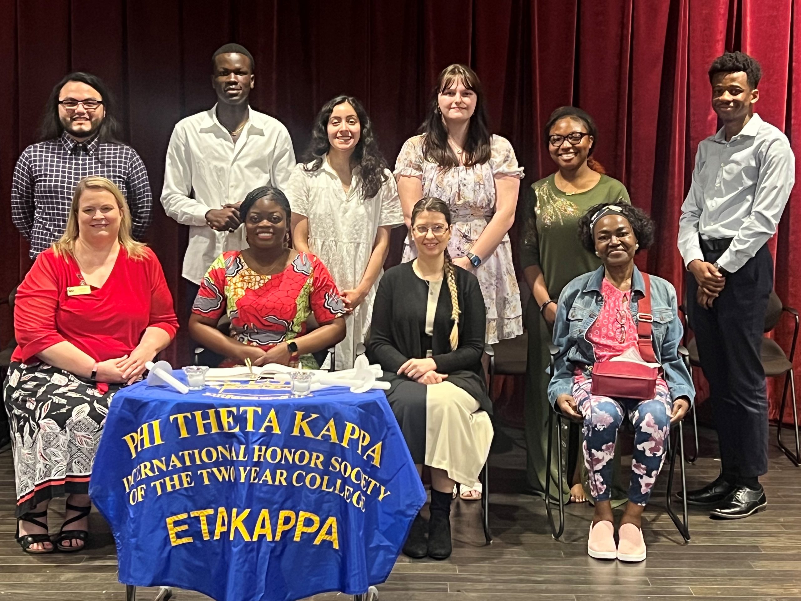 After setbacks, immigrant’s dream of attending college comes true 10 people smiling at the camera while on a stage in a theatre.
