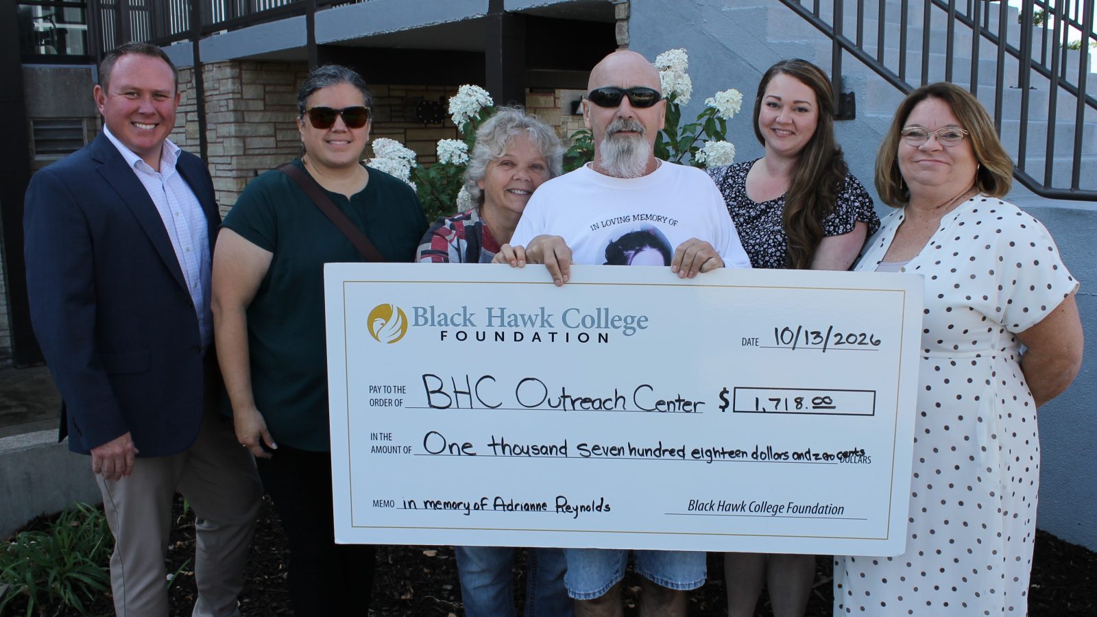 Reynolds family donates $1,718 to help ged® students 6 people standing outdoors with oversized check.