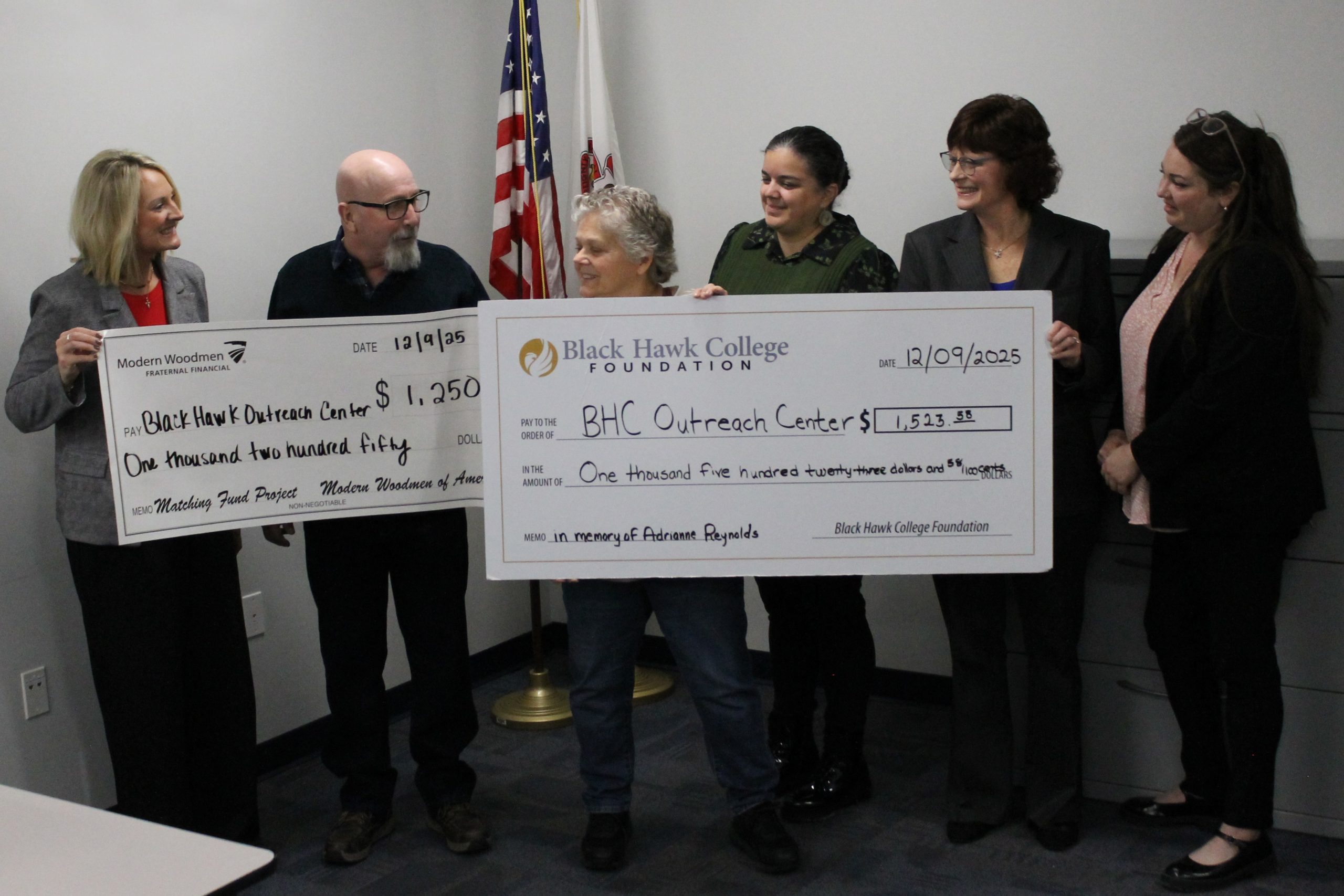 6 people standing with 2 oversized checks.