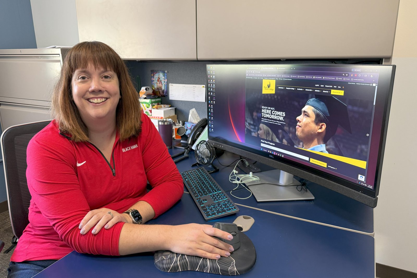 Smiling woman at computer desk.
