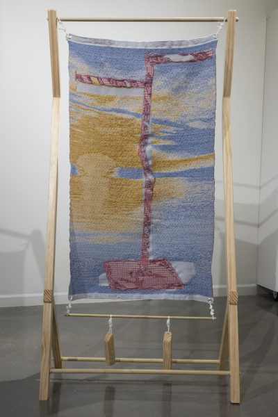 Woven artwork suspended in a wooden frame.