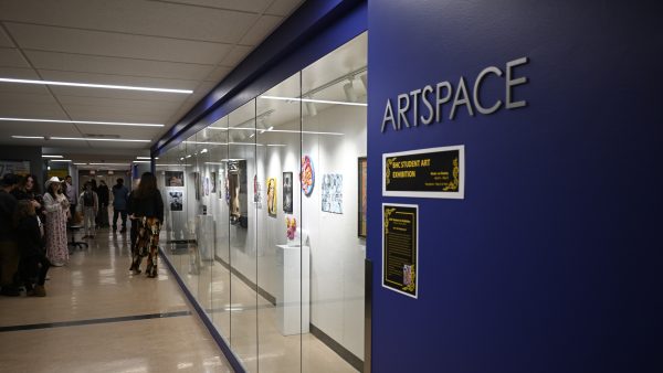 Wall of art displayed behind glass with text artspace on the wall.