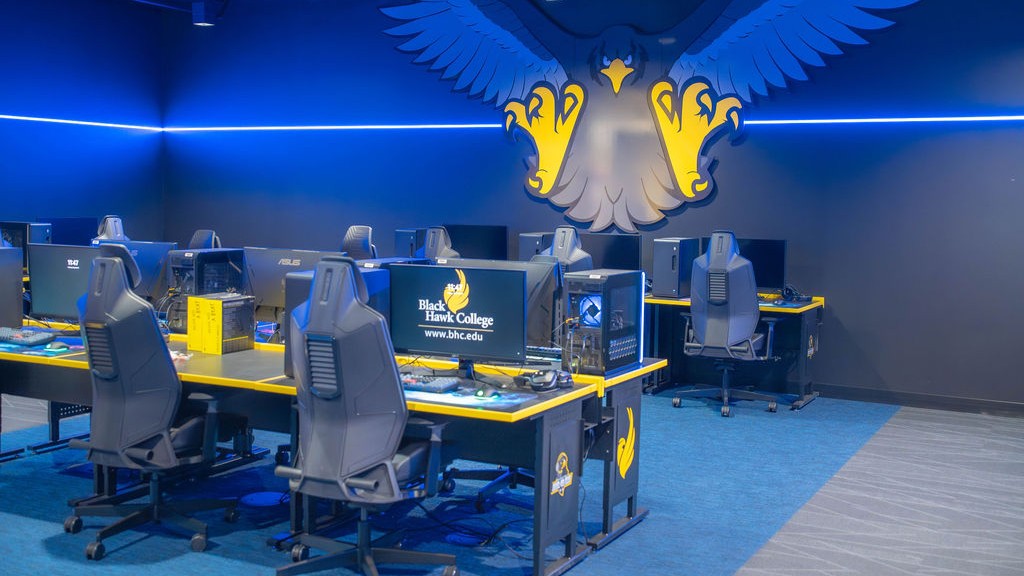 Bhc, community celebrate building 2 renovation 3 rows of tables with gaming computers and chairs and illustration of fierce hawk logo on wall.