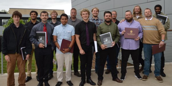 14 people standing outdoors and smiling at camera