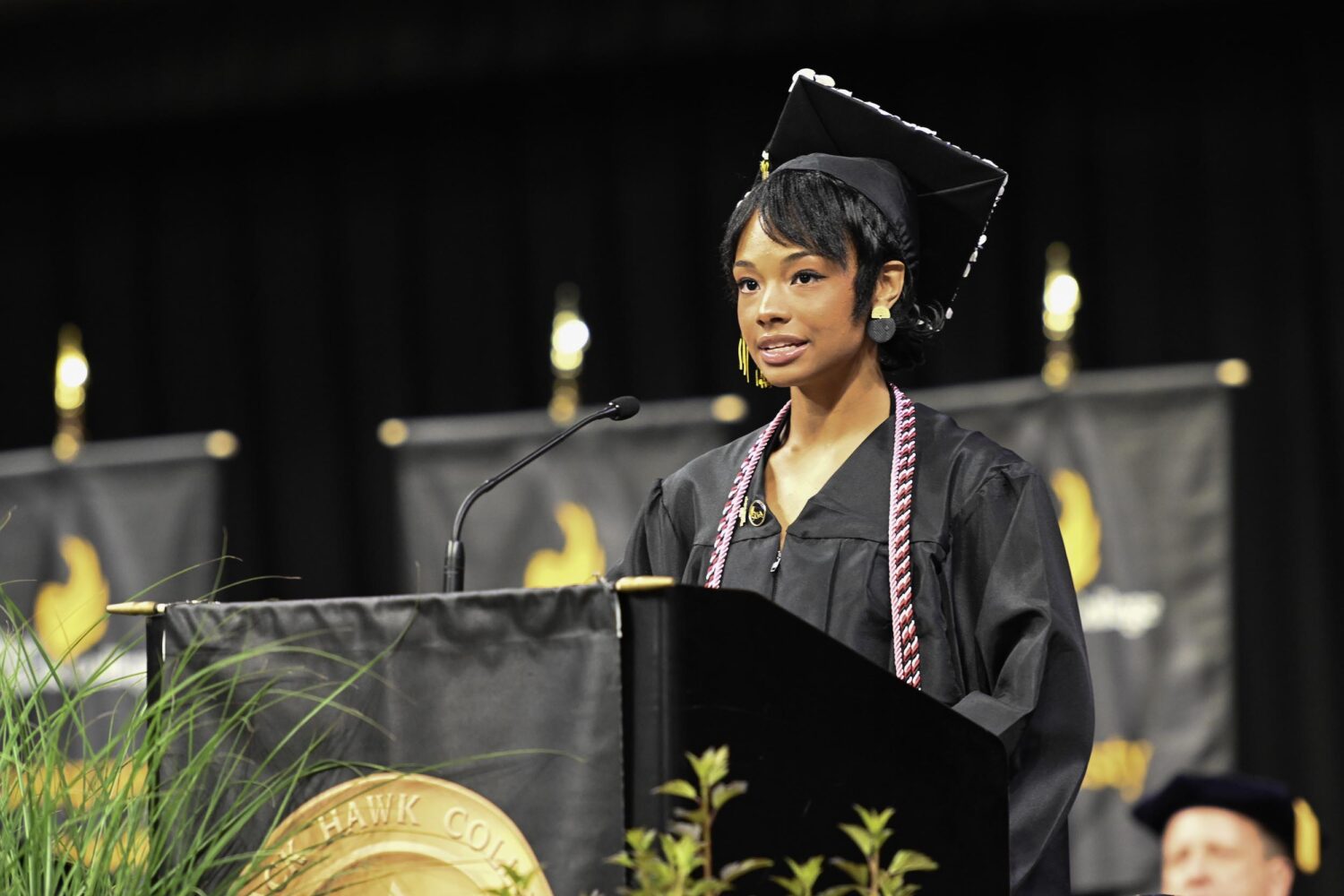 A woman in a graduation gown and cap standing at a podium