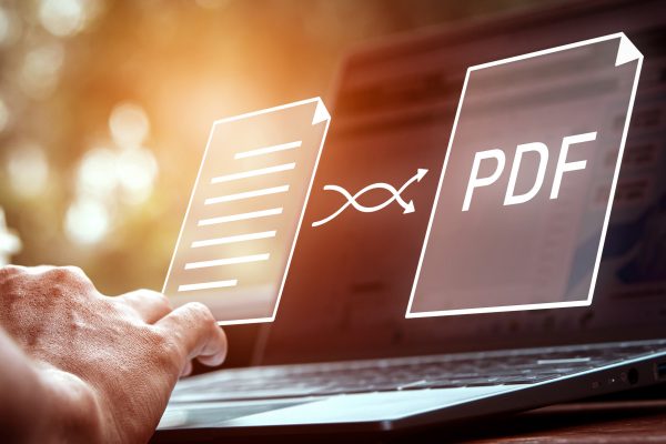 Convert pdf files with online programs. Users convert document files on a platform using an internet connection at desks. Concept of technology transforms documents into portable document formats.