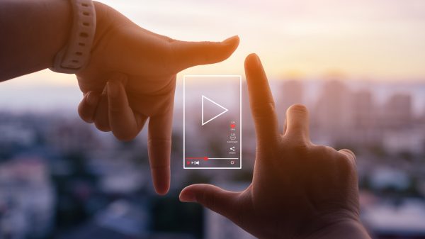 Hands framing a play button graphic