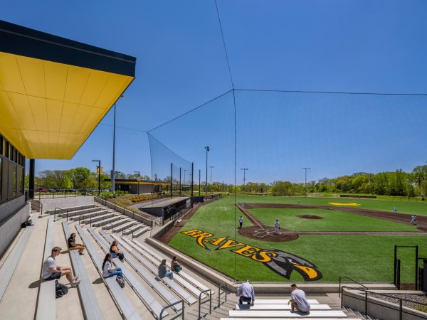 Sunny baseball field with spectators seated.