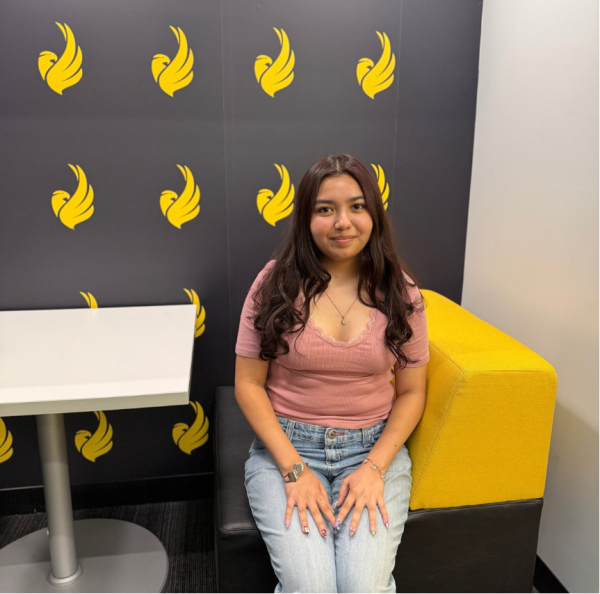 Girl sitting on seated booth in front of logoed wall, next to table