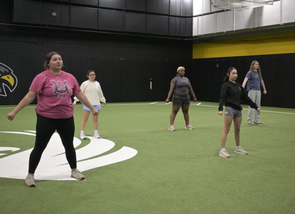 Spirit squad brings school pride to qc campus Students hitting cheer poses at spirit squad camp in turf room in building 3.