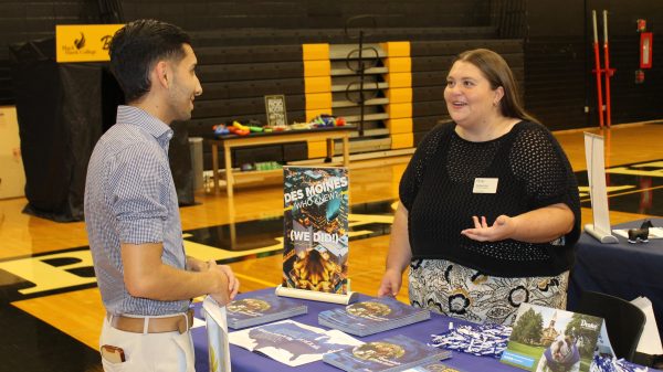 College night 2 people standing and talking at a table at college night.