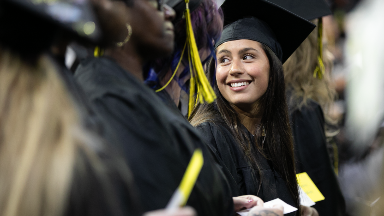 Excited female graduate in a crowd at a commencement ceremony.