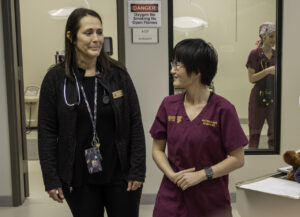 A woman standing next to a woman wearing scrubs, health sciences admissions