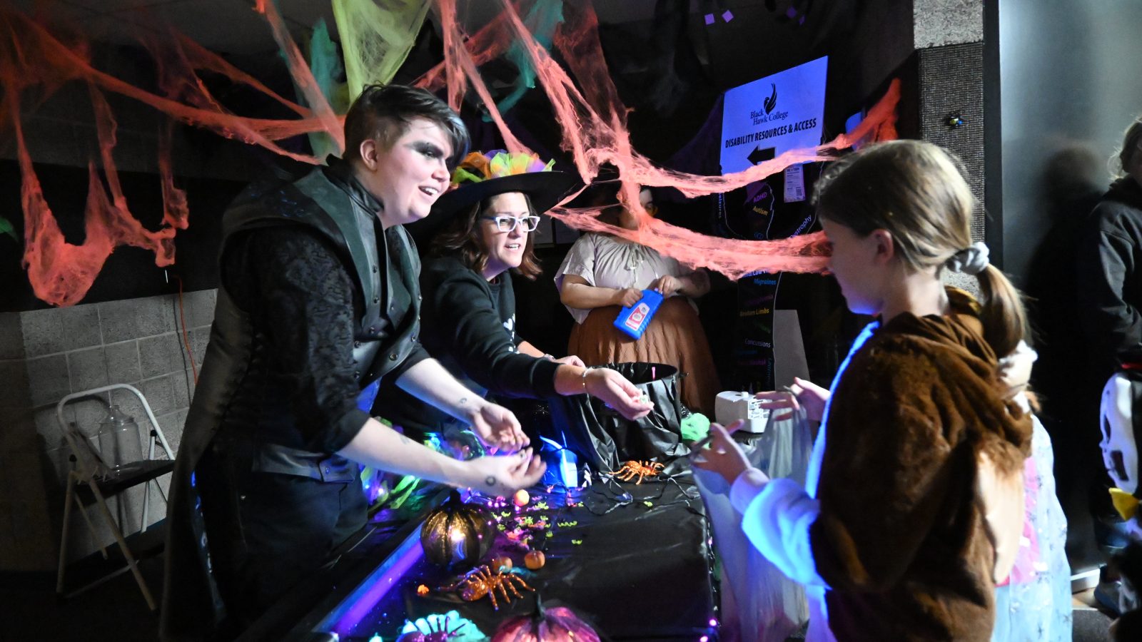 Two people passing out candy to children dressed up
