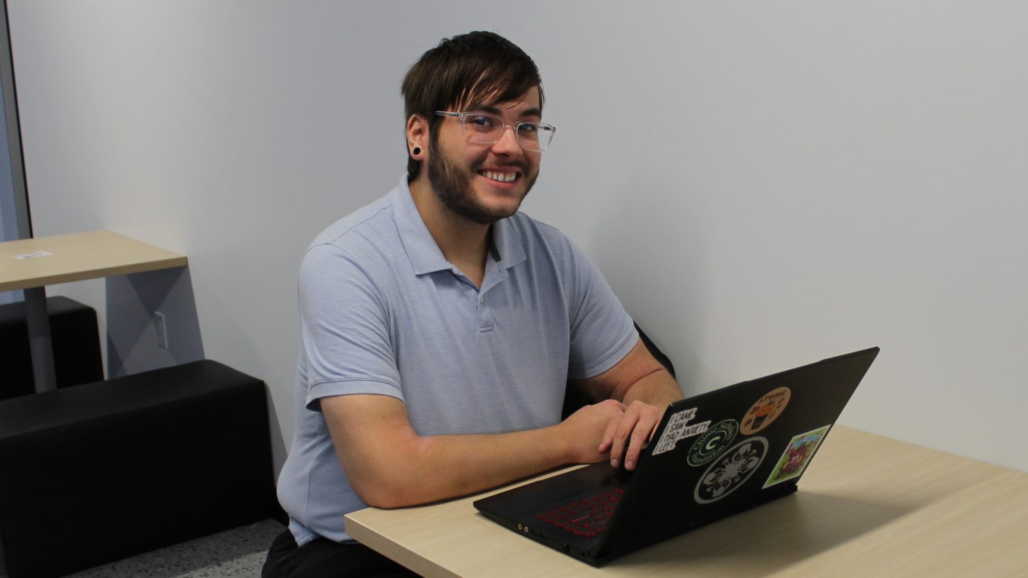 From high school dropout to honor student Man sitting at table with laptop and smiling at the camera.