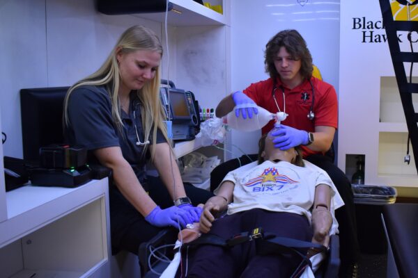 2 ems students working on a manikin patient in ambulance simulator.