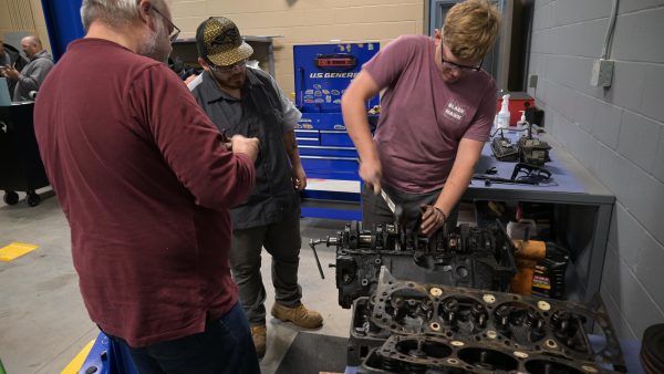 Three people working on an engine.