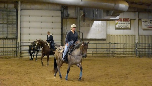 Academic departments Riders practicing in indoor arena.