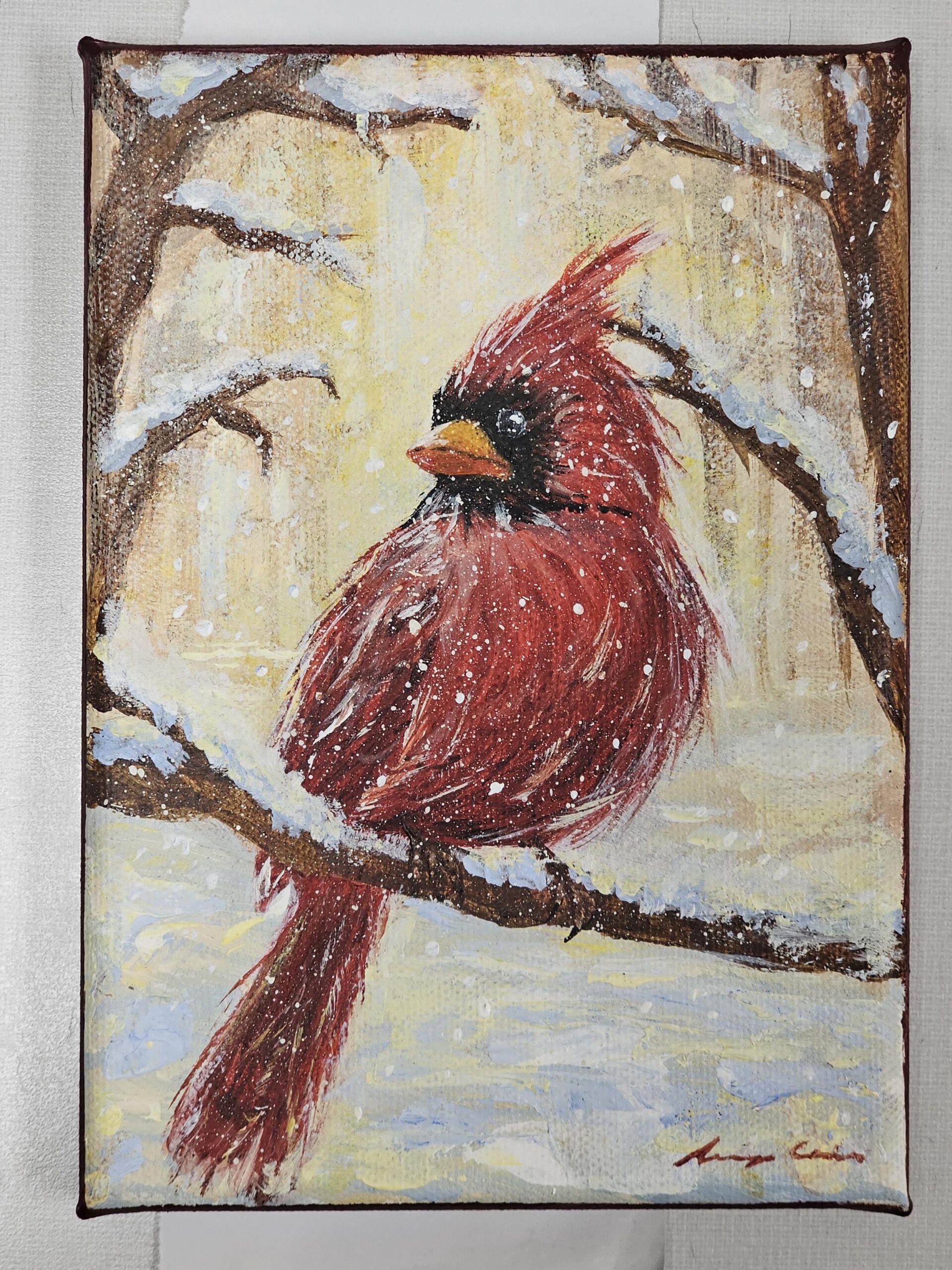 painting of bright red cardinal sitting on a snowy tree branch