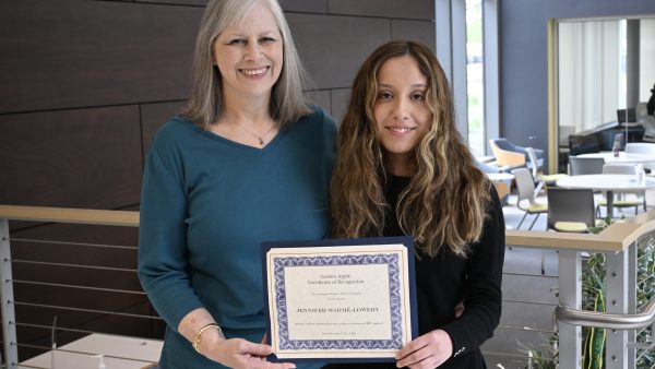 two people standing, holding a certificate and smiling at the camera.