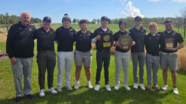 9 people standing on a golf course and holding awards.