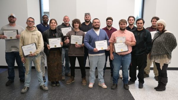 14 people standing and smiling at camera.