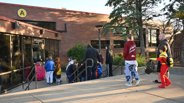 children and parents dressed up for Halloween to walk into a building